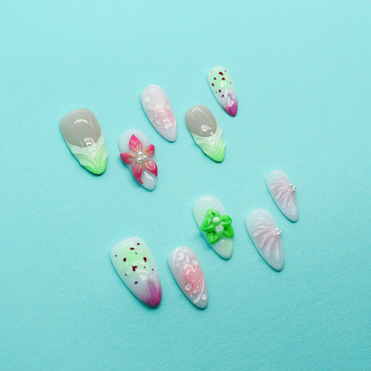Medium Almond press-on nails with strawberry-seed patterns, green and pink ombré tips, and 3D floral accents in bright green and pink.