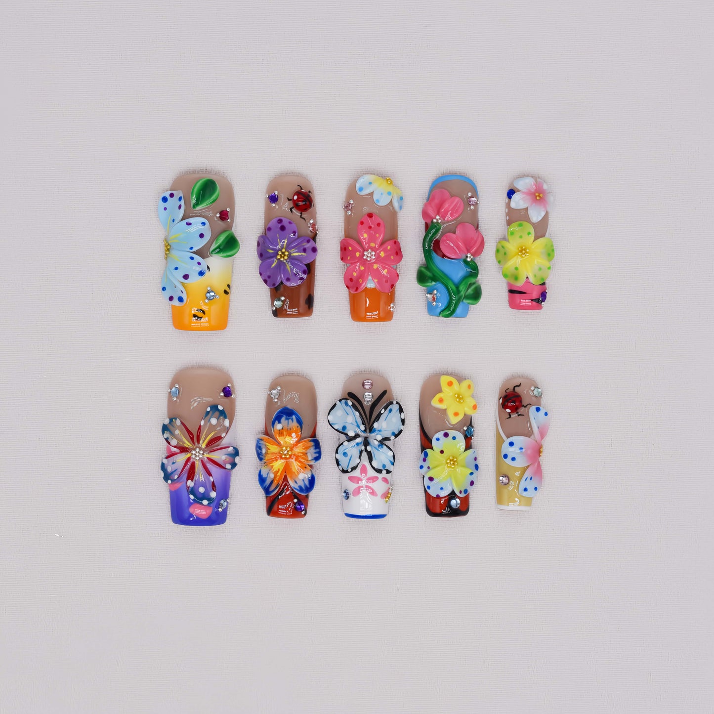 Handmade colorful floral press-on nails with 3D flower art, butterfly-inspired details, rhinestones, and glossy artistic finish