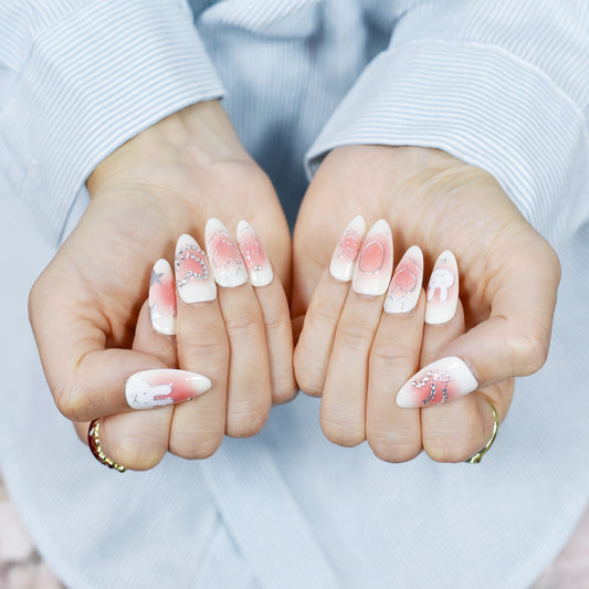 Close-up of hands with pink and white nail art on a light background