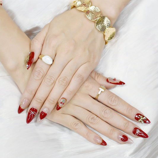 Cherry Kiss & Crimson Bows press-on nails with red and nude tones, 3D cherry and gold bow charms, heart and ribbon accents, almond shape.