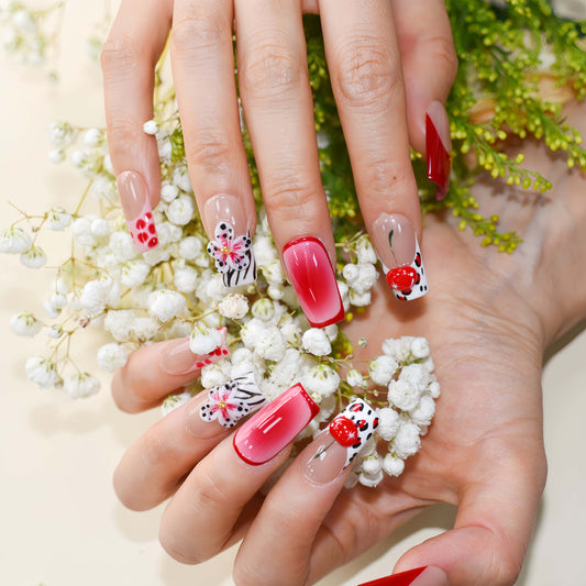 Handmade cherry-red floral press-on nails with glossy ombré finish, cherry accents, and elegant black-and-white artistic nail art