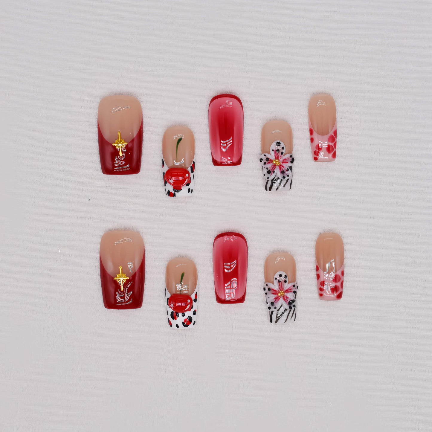 Handmade cherry-red floral press-on nails with glossy ombré finish, cherry accents, and elegant black-and-white artistic nail art