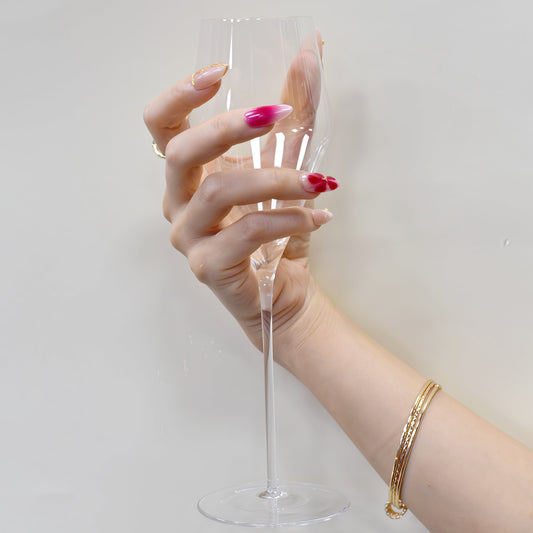 Medium almond press-on nails in nude and crimson ombré with white florals, gold beads, and sculpted gold frame.