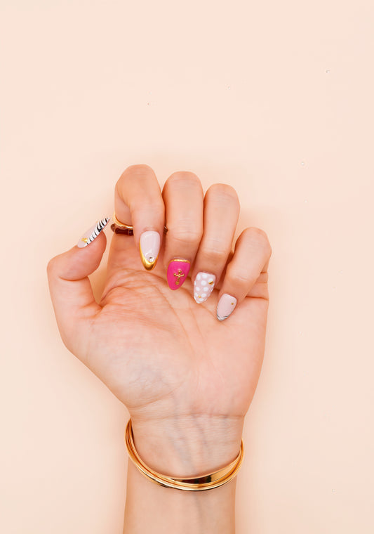 Almond press-on nails with zebra stripes, pink 3D shells, polka dots, gold cross embellishments, and chrome gold tip – Electric Pop Royale set.