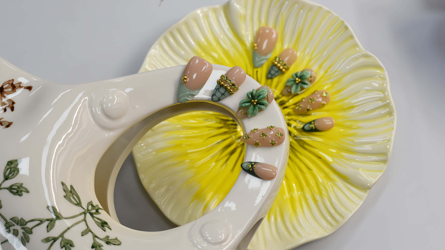 Sage green floral press on nails with gold embellishments and delicate botanical artwork.