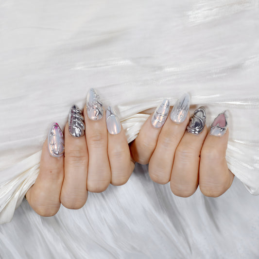 Medium Almond press-on nails with chrome textures, sculptural 3D hearts and swirls, and pearlescent nude base — Silver Luster Muse.