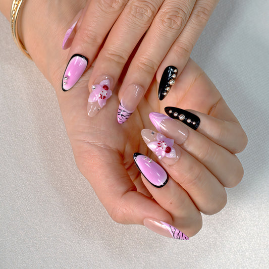 Medium Almond press-on nails in pink ombré with black zebra print, 3D orchid flowers, and rhinestone-studded accents.
