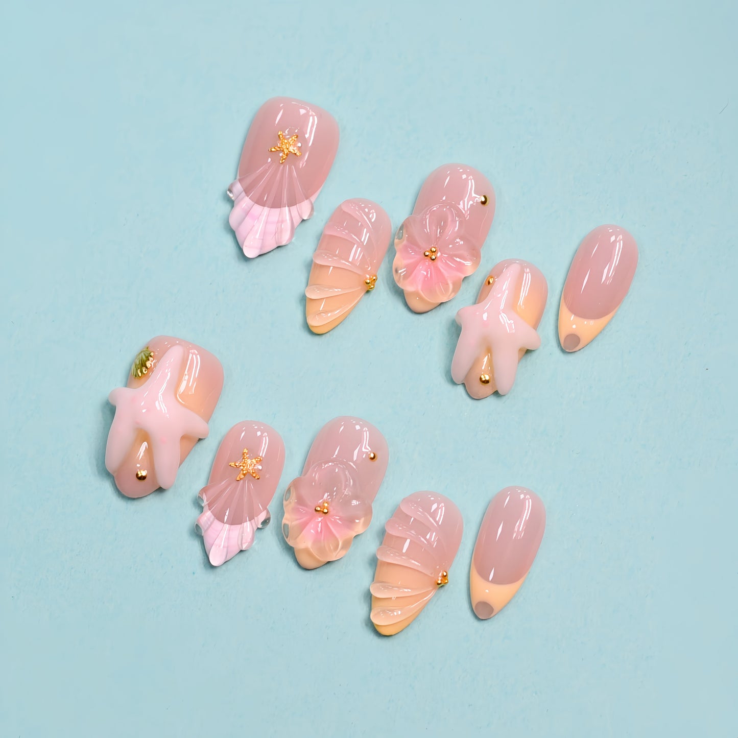 Seaside Bliss 3D press-on nails set with blush pink ombré base, sculpted starfish charms, pink ribbon bows and scallop shell nail art on teal background