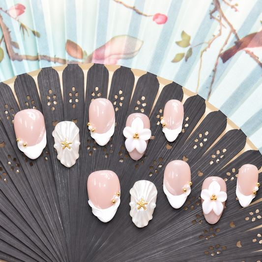 Pearl Tide Blossom blush press-on nails with white petals, pearls and gold starfish details — styled product photograph.