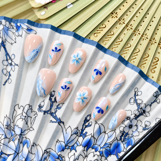 Blue Porcelain Bloom nude press-on nails with cobalt flowers, turquoise leaves and silver linework — styled product photograph.