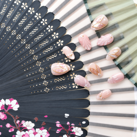 Rose Gold Leaf Veil peach press-on nails with translucent leaves, pearls and fine gold outlines — styled product photograph.