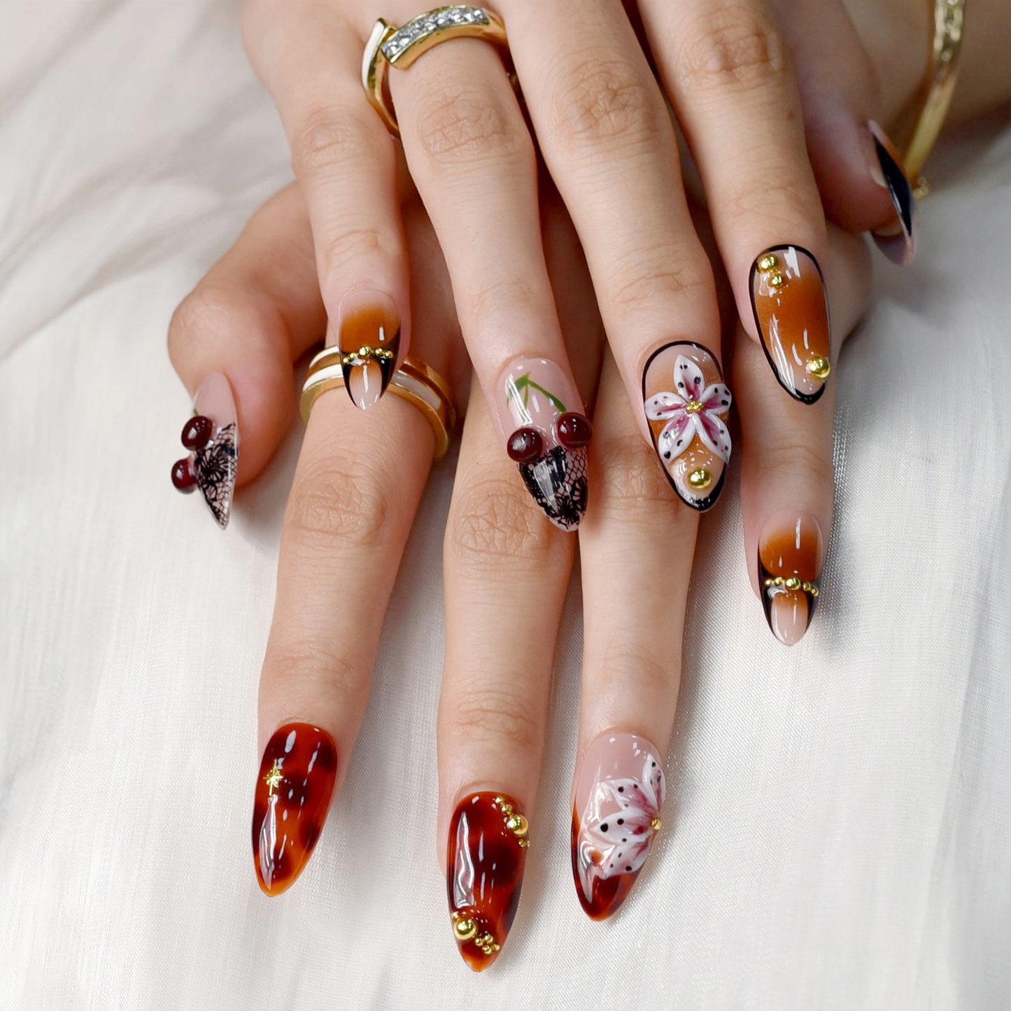 Autumn-inspired press-on nails with orange and amber tones, floral and lace details.