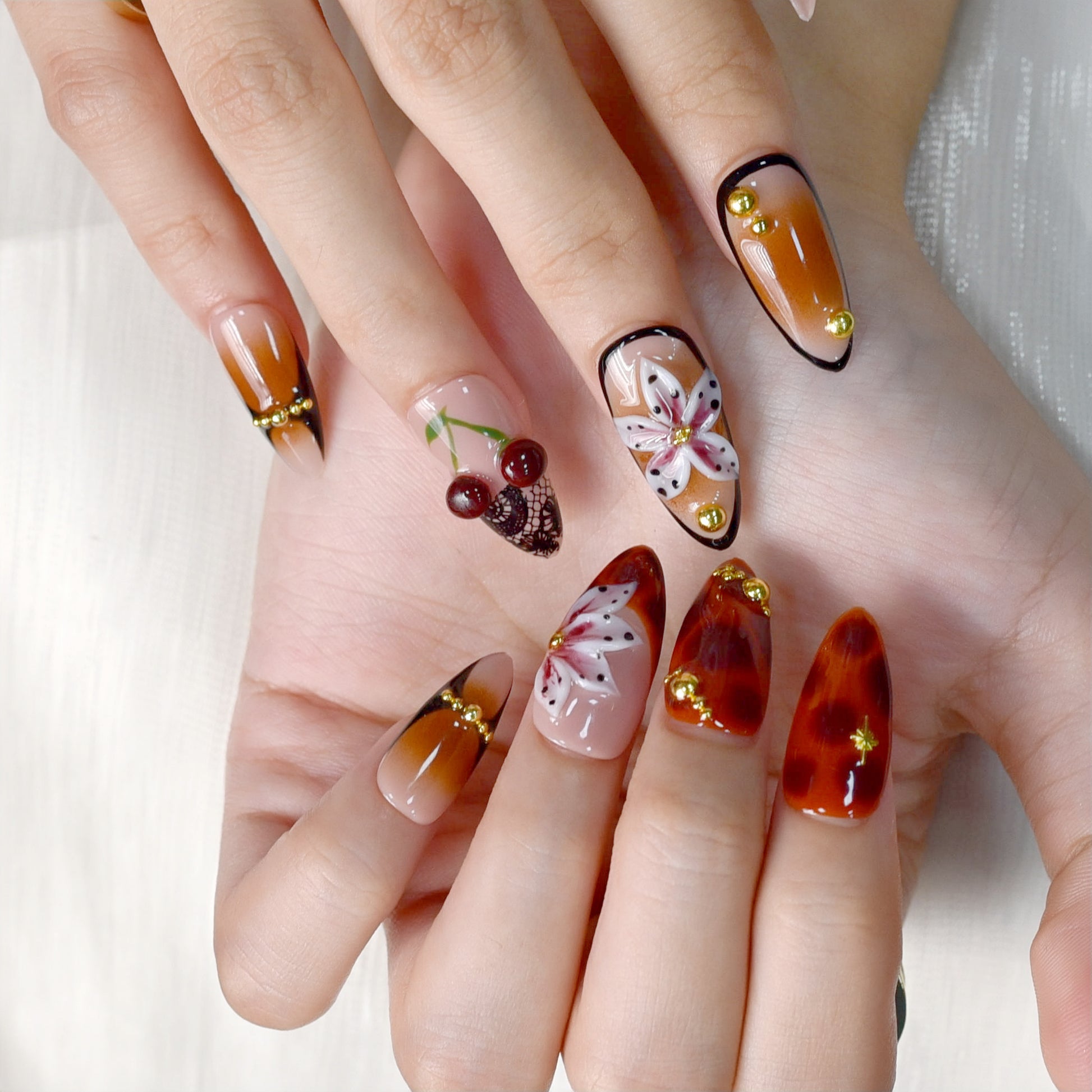 Autumn-inspired press-on nails with orange and amber tones, floral and lace details.