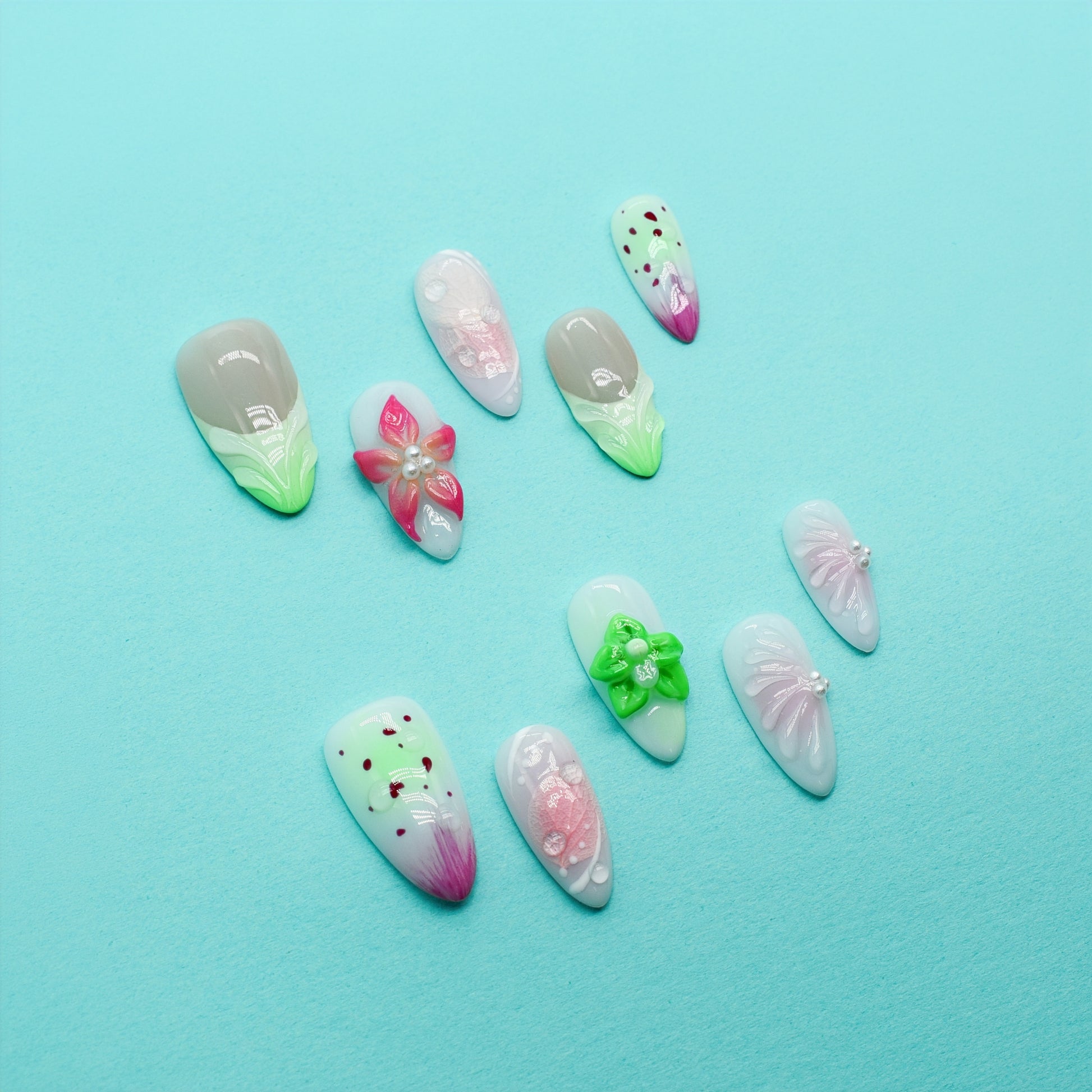 Medium Almond press-on nails with strawberry-seed patterns, green and pink ombré tips, and 3D floral accents in bright green and pink.