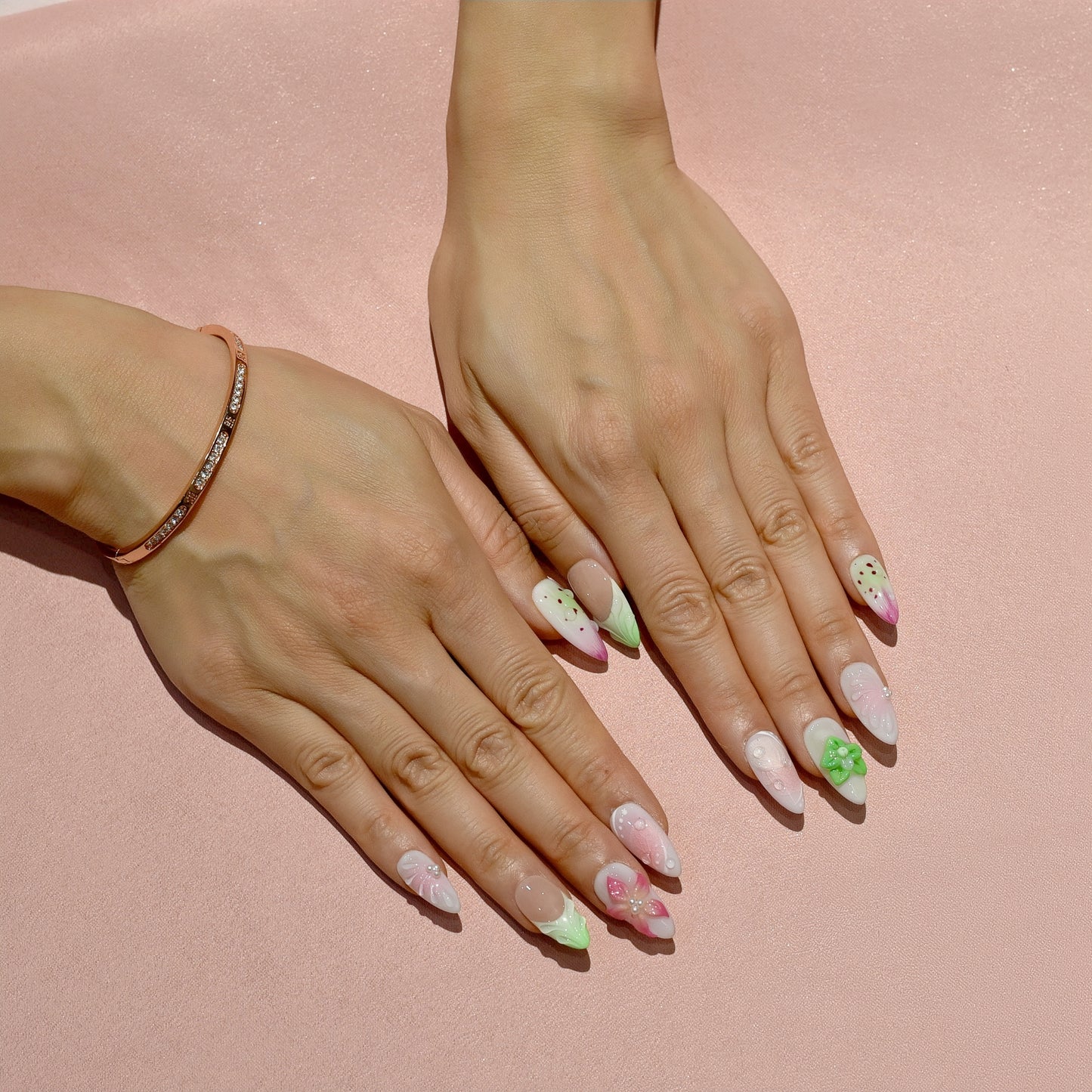 Medium Almond press-on nails with strawberry-seed patterns, green and pink ombré tips, and 3D floral accents in bright green and pink.