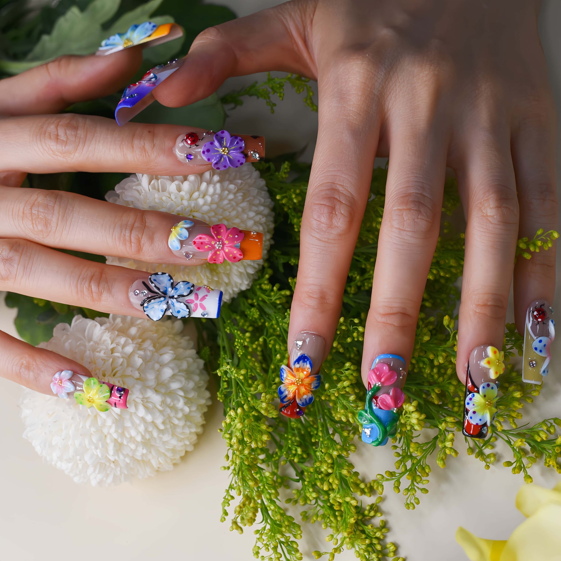 Handmade colorful floral press-on nails with 3D flower art, butterfly-inspired details, rhinestones, and glossy artistic finish