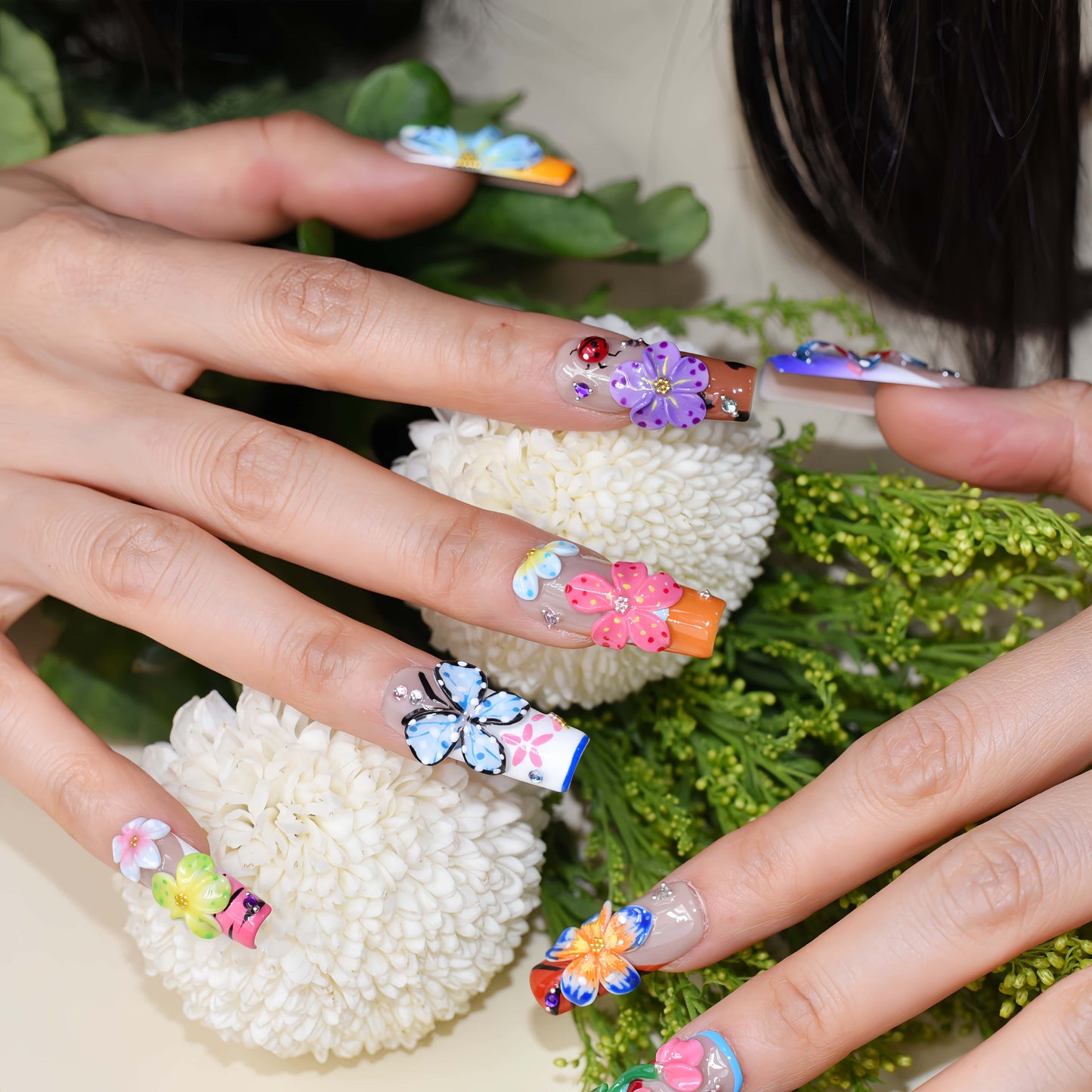 Handmade colorful floral press-on nails with 3D flower art, butterfly-inspired details, rhinestones, and glossy artistic finish
