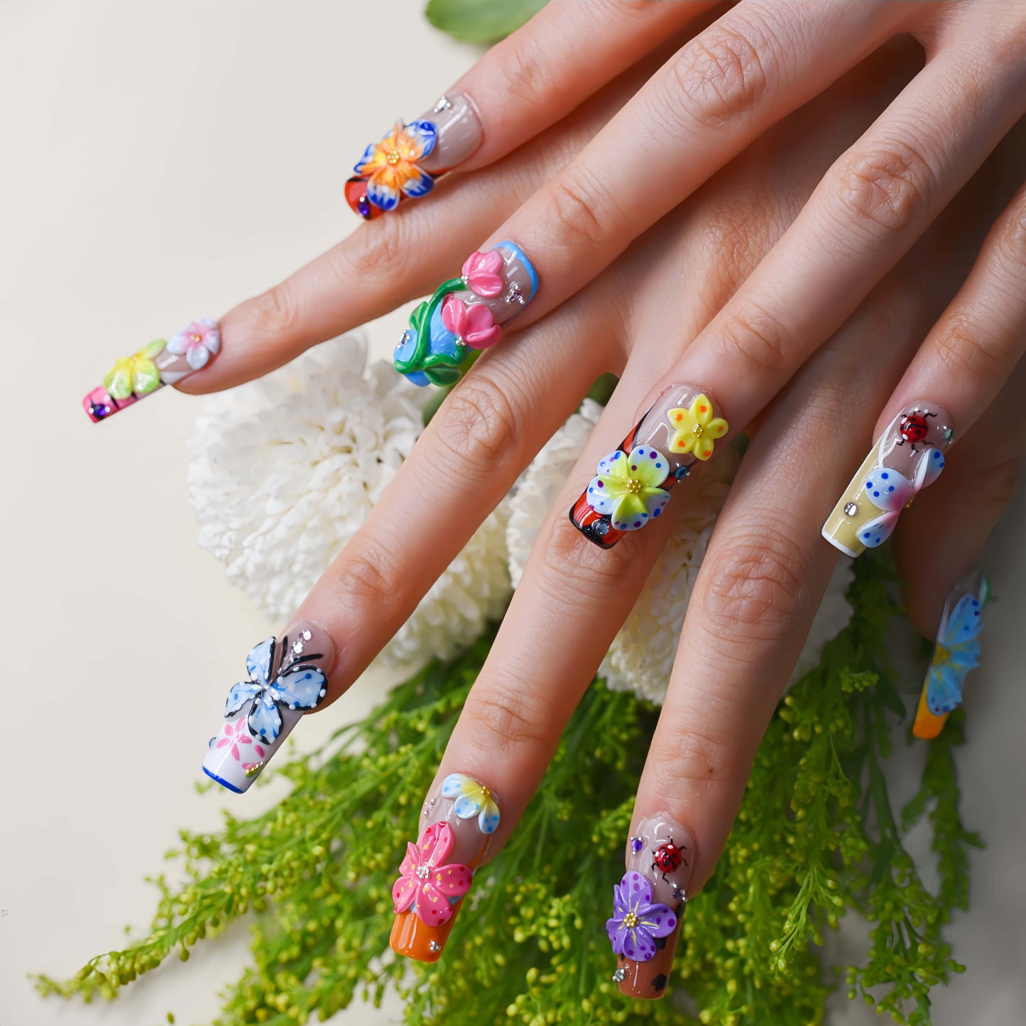 Handmade colorful floral press-on nails with 3D flower art, butterfly-inspired details, rhinestones, and glossy artistic finish