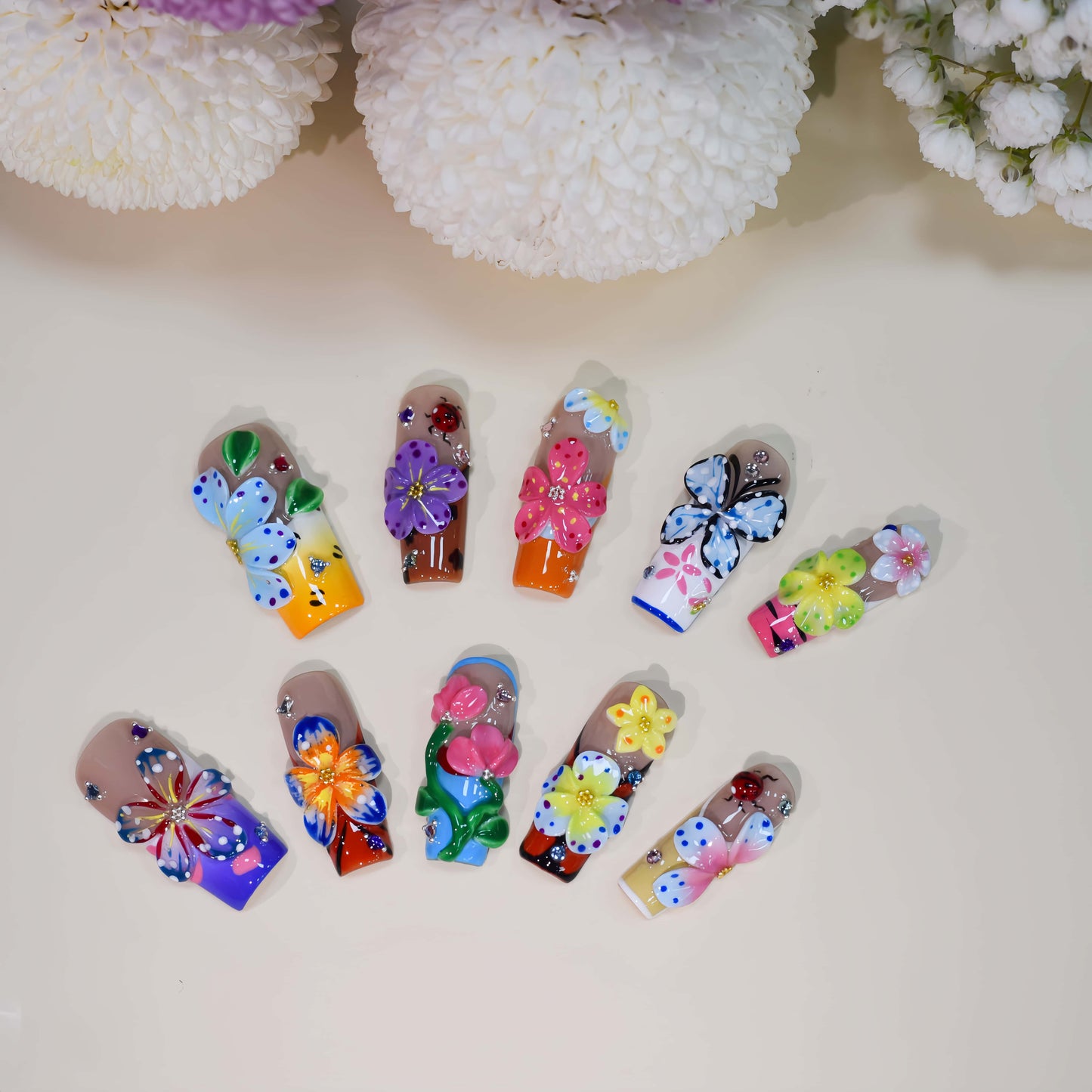 Handmade colorful floral press-on nails with 3D flower art, butterfly-inspired details, rhinestones, and glossy artistic finish