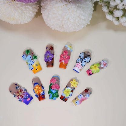 Handmade colorful floral press-on nails with 3D flower art, butterfly-inspired details, rhinestones, and glossy artistic finish
