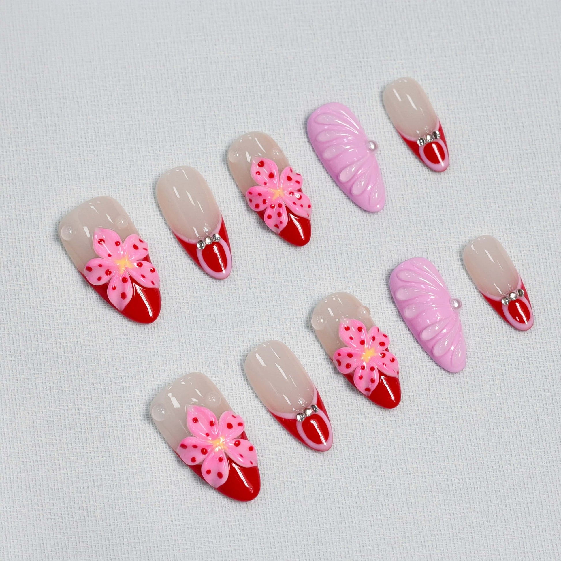 Blooming Amour 3D floral press-on nails featuring red French tips, pink flower accents, and glossy nude base.