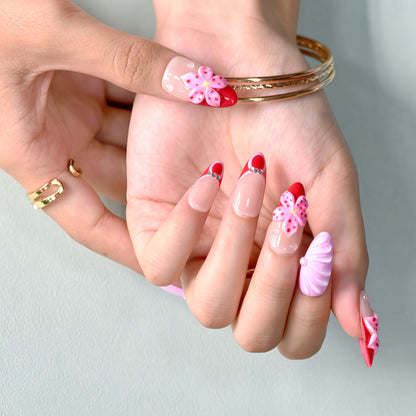 Blooming Amour 3D floral press-on nails featuring red French tips, pink flower accents, and glossy nude base.