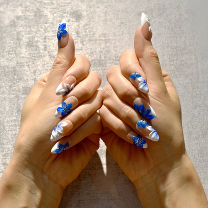 Blue Blossom almond press-on nails with French tips and vivid blue floral accents – Tropical Bloom Collection.