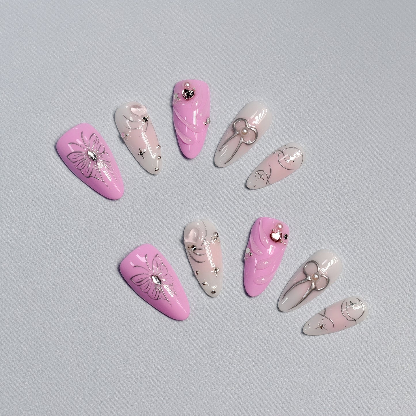 Pink and silver butterfly & bow press-on nails with rhinestone details – handcrafted romantic nail art.