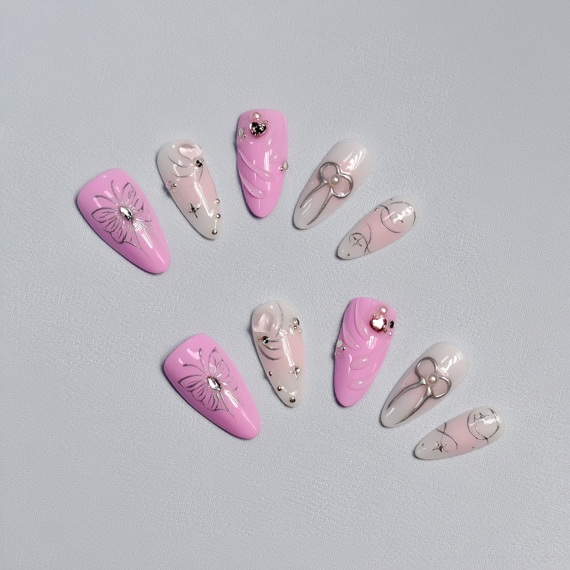 Pink and silver butterfly & bow press-on nails with rhinestone details – handcrafted romantic nail art.