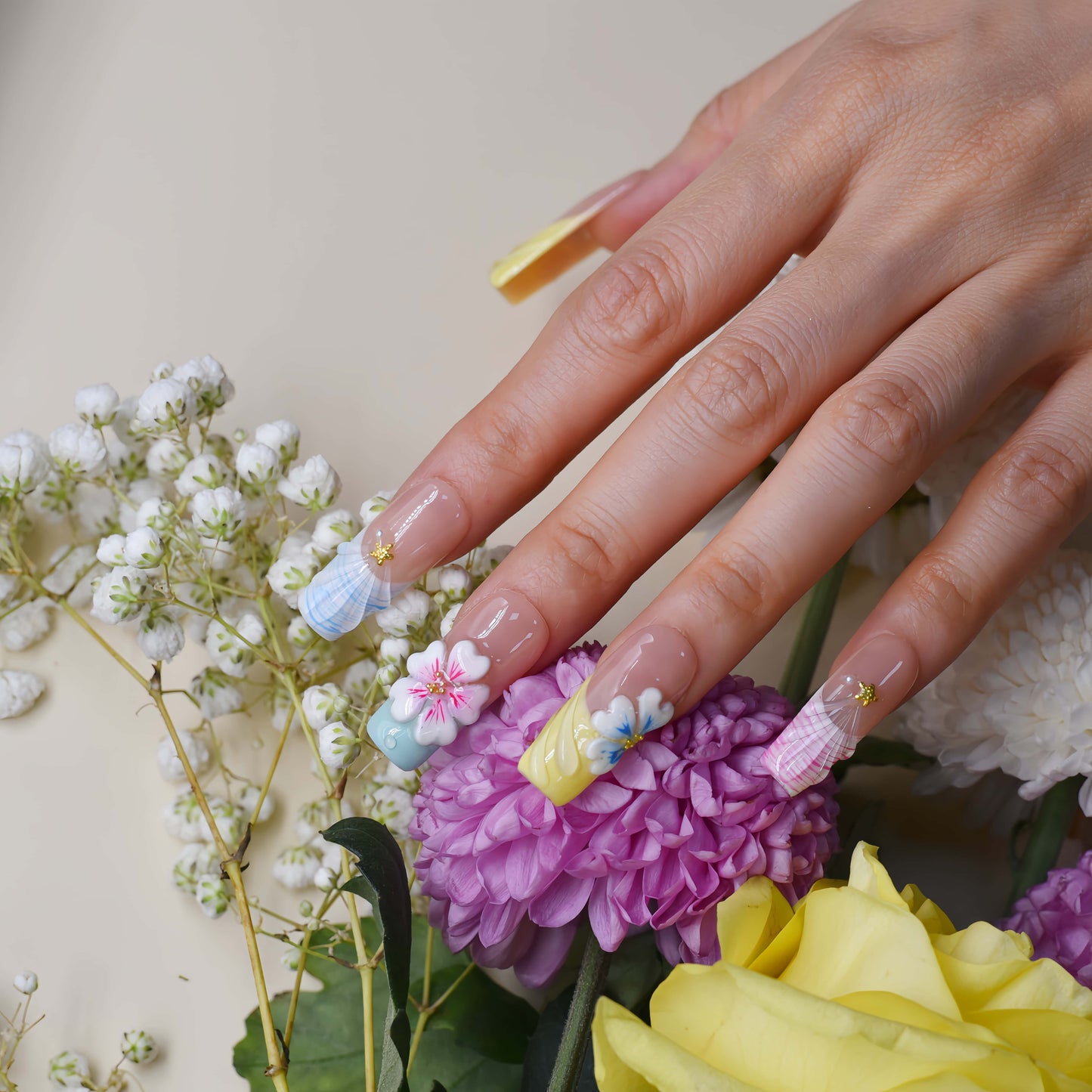 Handmade pastel floral press-on nails with 3D flower art, glossy sculpted details, and soft spring-inspired colors