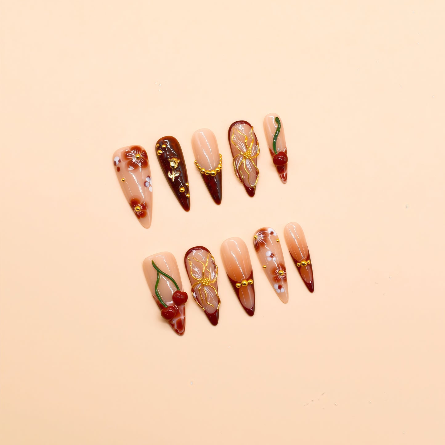Long stiletto press-on nails in deep red gradient with 3D cherries, gold flowers, and floral hand-painted designs – Cherry Ember by You Are Angel.