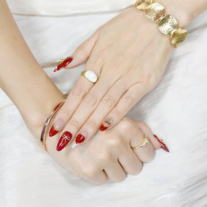 Cherry Kiss & Crimson Bows press-on nails with red and nude tones, 3D cherry and gold bow charms, heart and ribbon accents, almond shape.