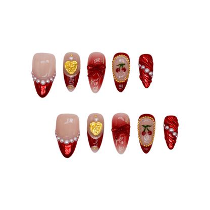 Cherry Luxe Charm press-on nails in red chrome and nude tones with pearl trims, gold accents, and cherry details — festive and elegant.