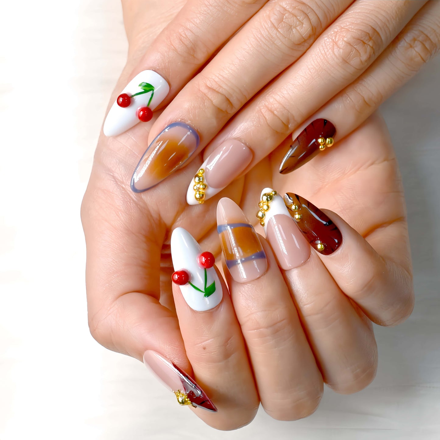 Cherry Mocha Bloom press-on nails featuring mocha brown tones, gold details, and red cherry accents with a glossy handmade finish.