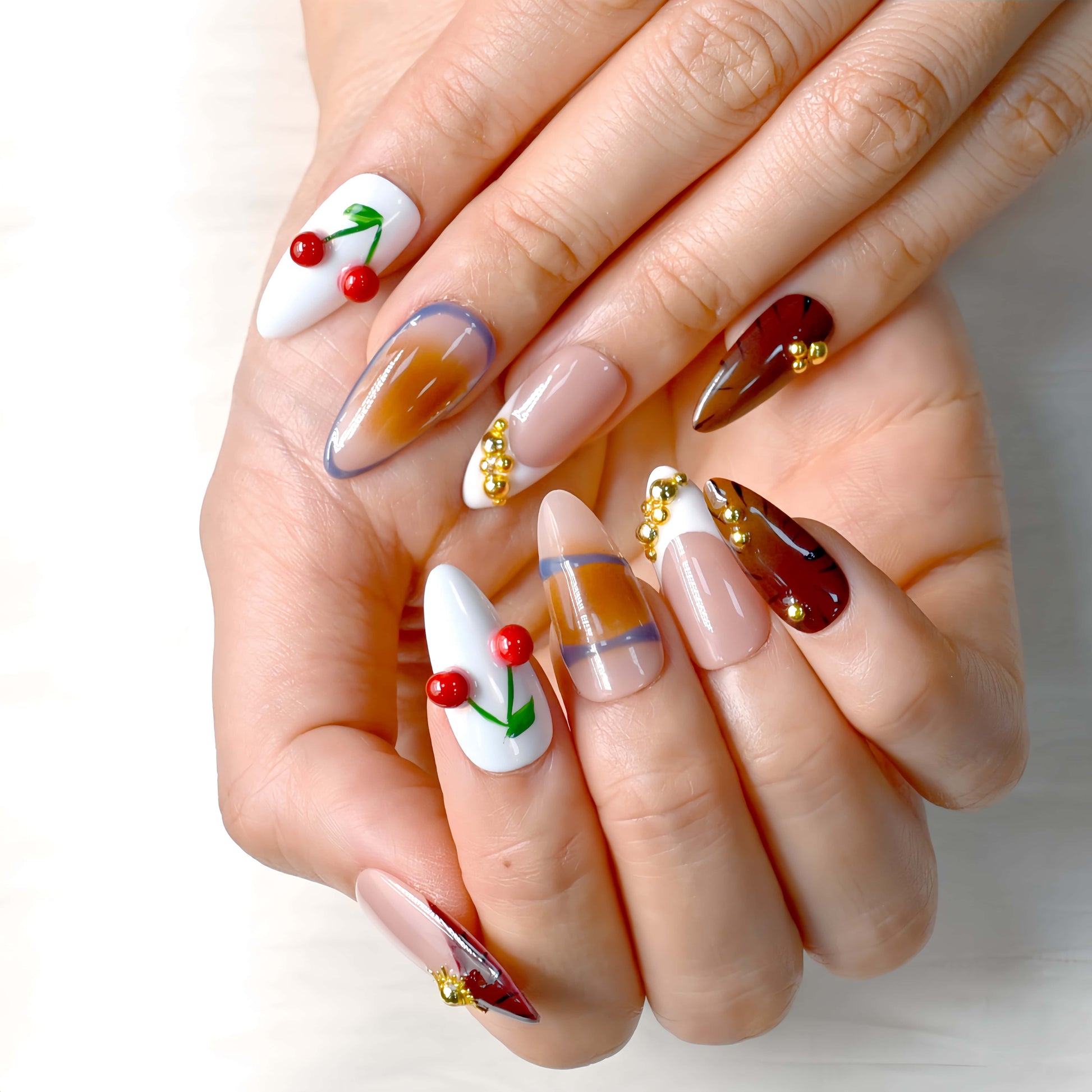 Cherry Mocha Bloom press-on nails featuring mocha brown tones, gold details, and red cherry accents with a glossy handmade finish.