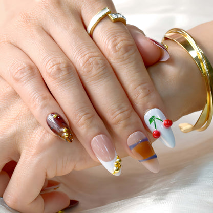 Cherry Mocha Bloom press-on nails featuring mocha brown tones, gold details, and red cherry accents with a glossy handmade finish.