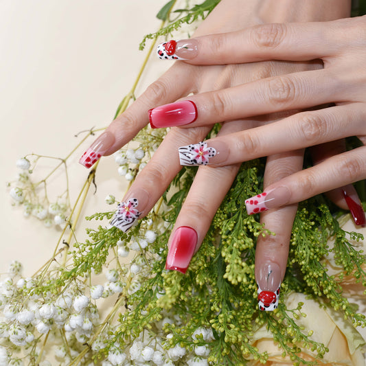 Handmade cherry-red floral press-on nails with glossy ombré finish, cherry accents, and elegant black-and-white artistic nail art