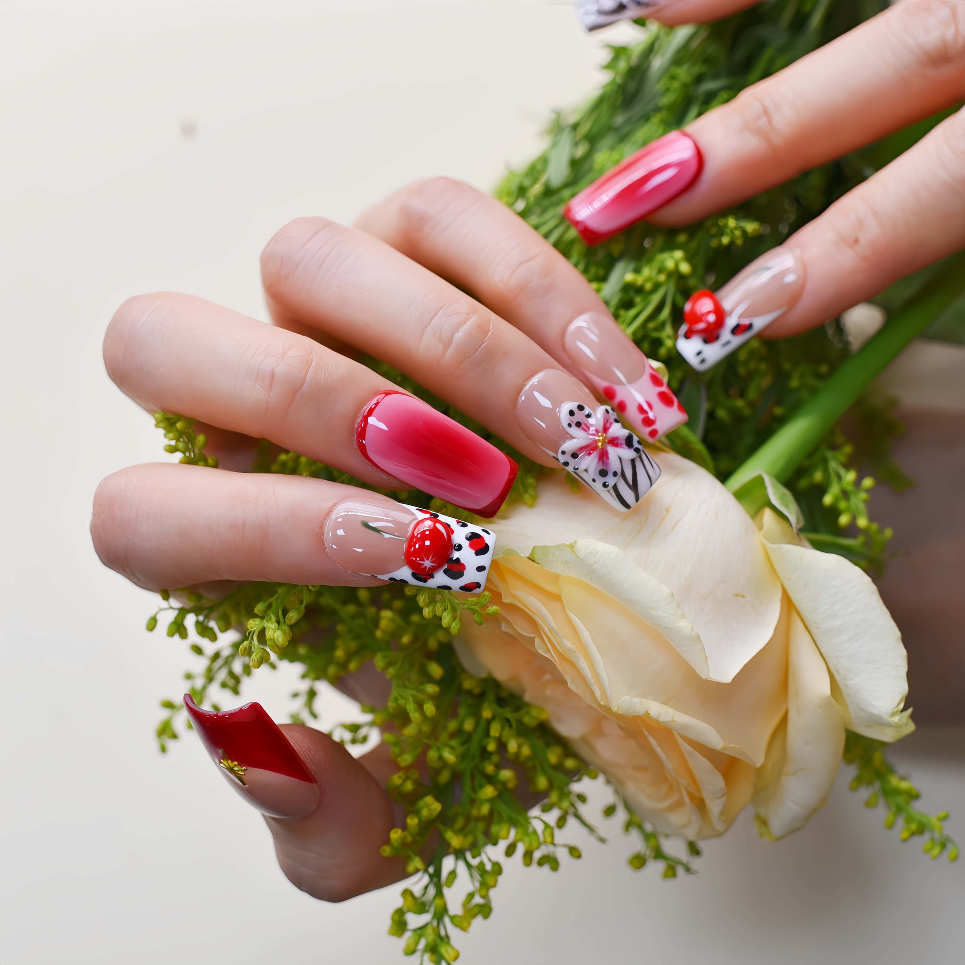 Handmade cherry-red floral press-on nails with glossy ombré finish, cherry accents, and elegant black-and-white artistic nail art