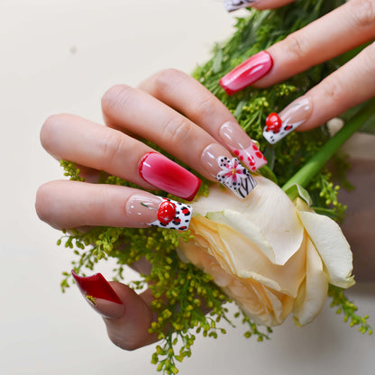 Handmade cherry-red floral press-on nails with glossy ombré finish, cherry accents, and elegant black-and-white artistic nail art