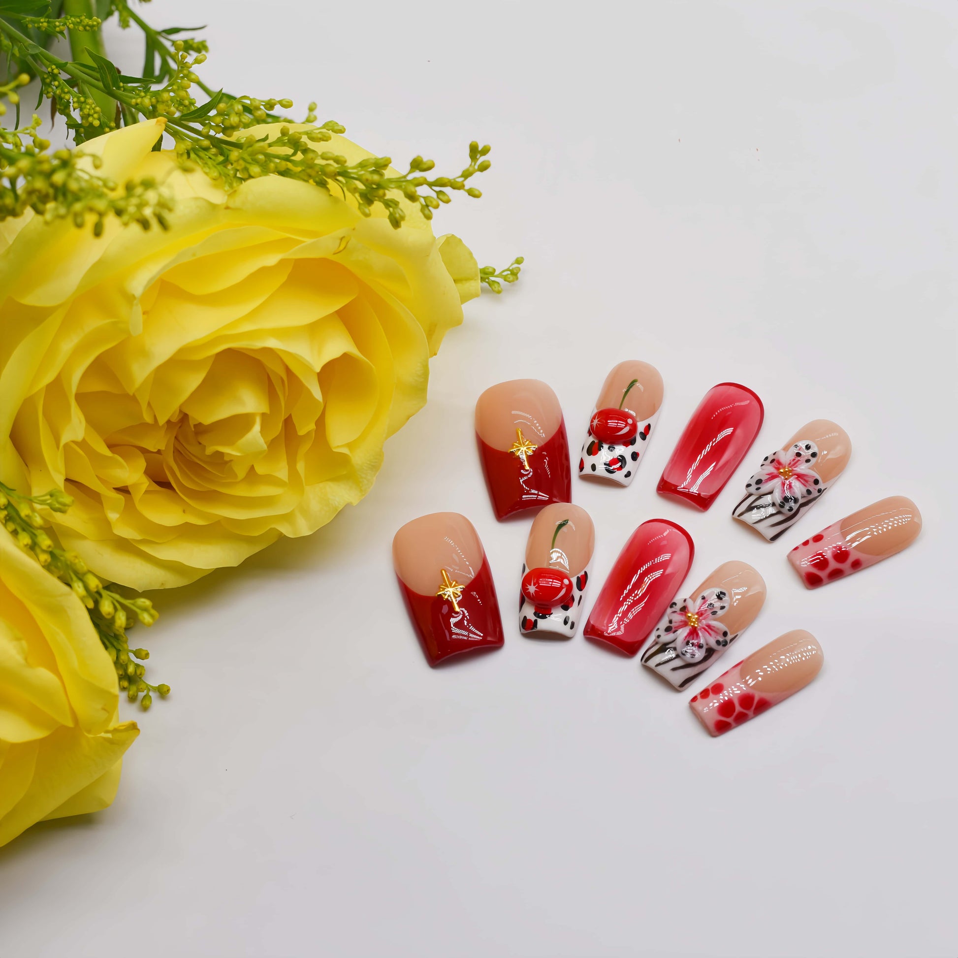 Handmade cherry-red floral press-on nails with glossy ombré finish, cherry accents, and elegant black-and-white artistic nail art