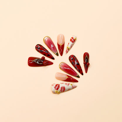 Handmade press-on nails in red, pink, and black with kiss print and cherry accents from You Are Angel.