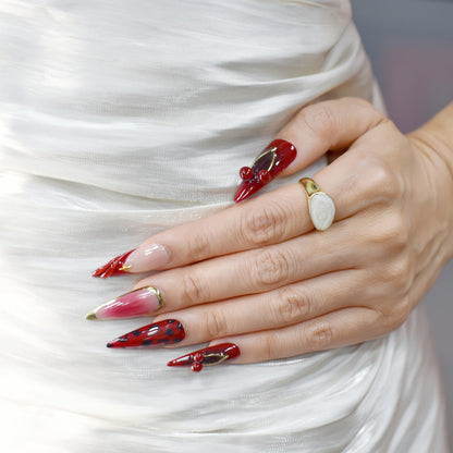 Set of red and pink nail art designs on a white fabric background
