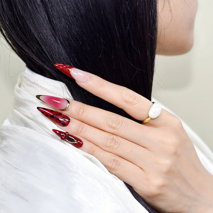 Close-up of a hand with red and pink nail polish holding black hair.