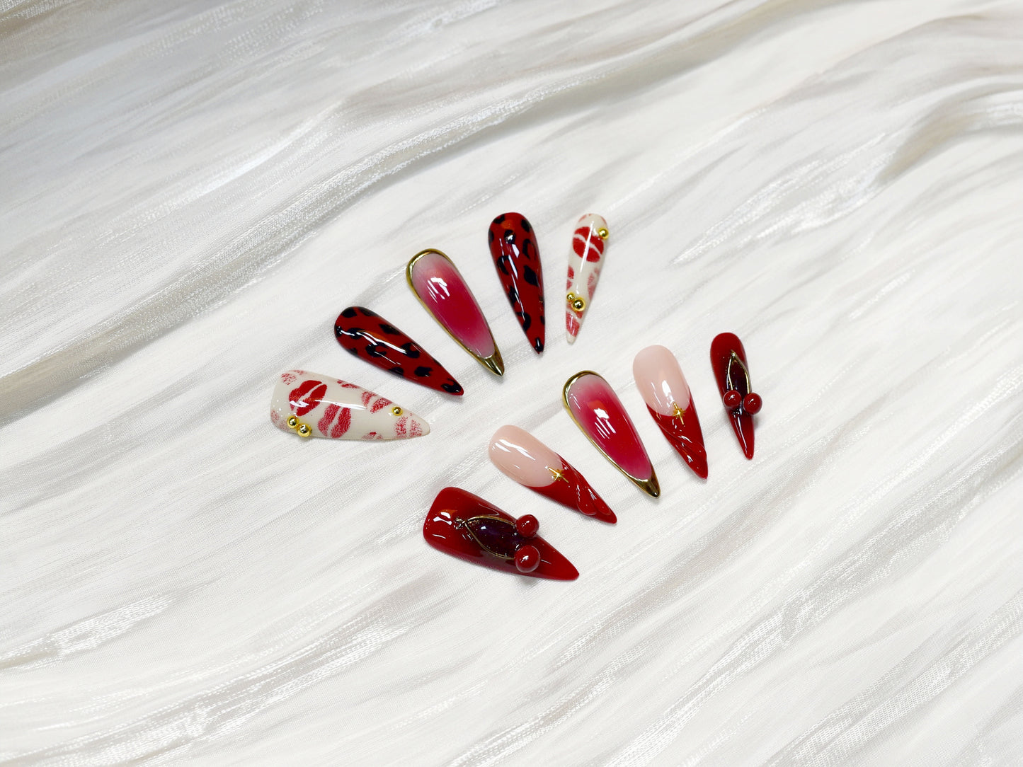 Handmade press-on nails in red, pink, and black with kiss print and cherry accents from You Are Angel.
