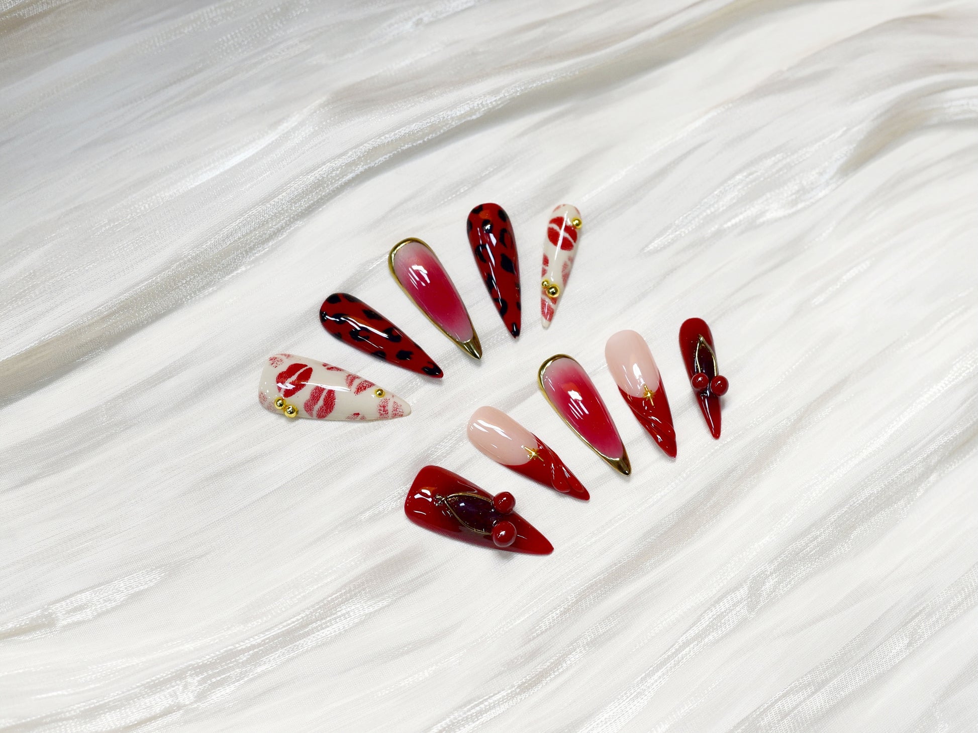 Handmade press-on nails in red, pink, and black with kiss print and cherry accents from You Are Angel.