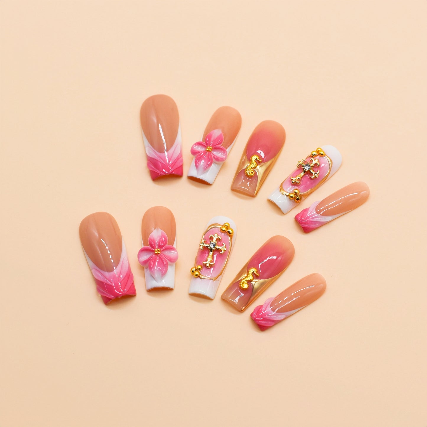 Long square press-on nails featuring coral pink ombre, gold crucifix charms, 3D pink flowers, and golden seahorse details – Coral Bloom Reverie nail set.