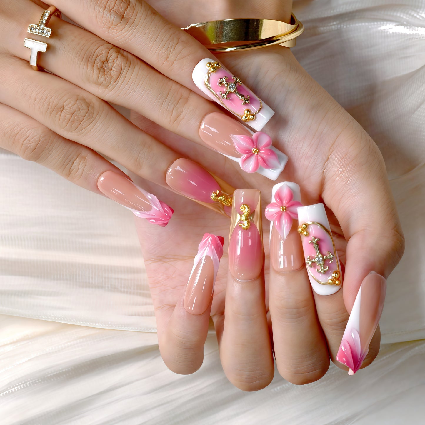 Long square press-on nails featuring coral pink ombre, gold crucifix charms, 3D pink flowers, and golden seahorse details – Coral Bloom Reverie nail set.