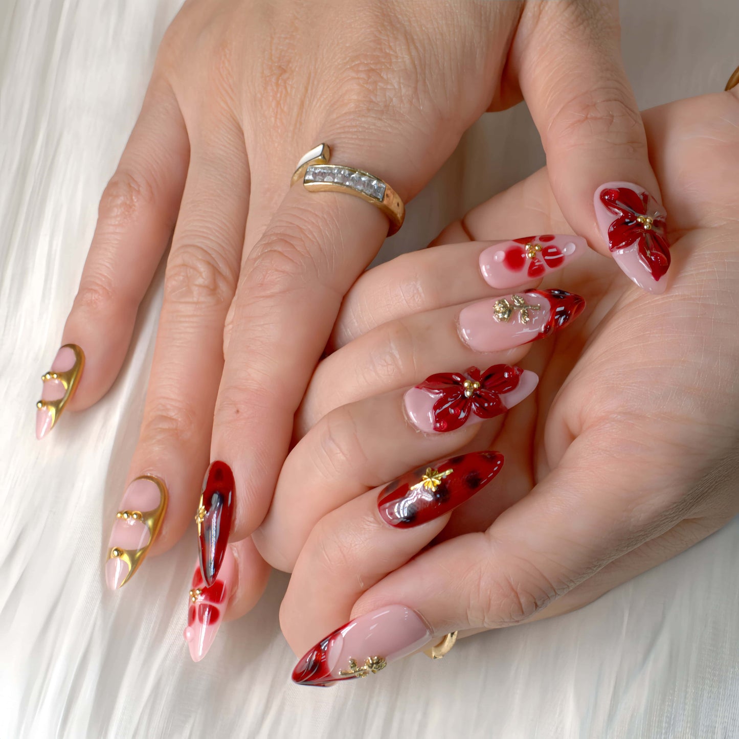 Crimson Bloom press-on nails featuring deep red floral 3D designs, gold details, and glossy pink base for an elegant, romantic look.