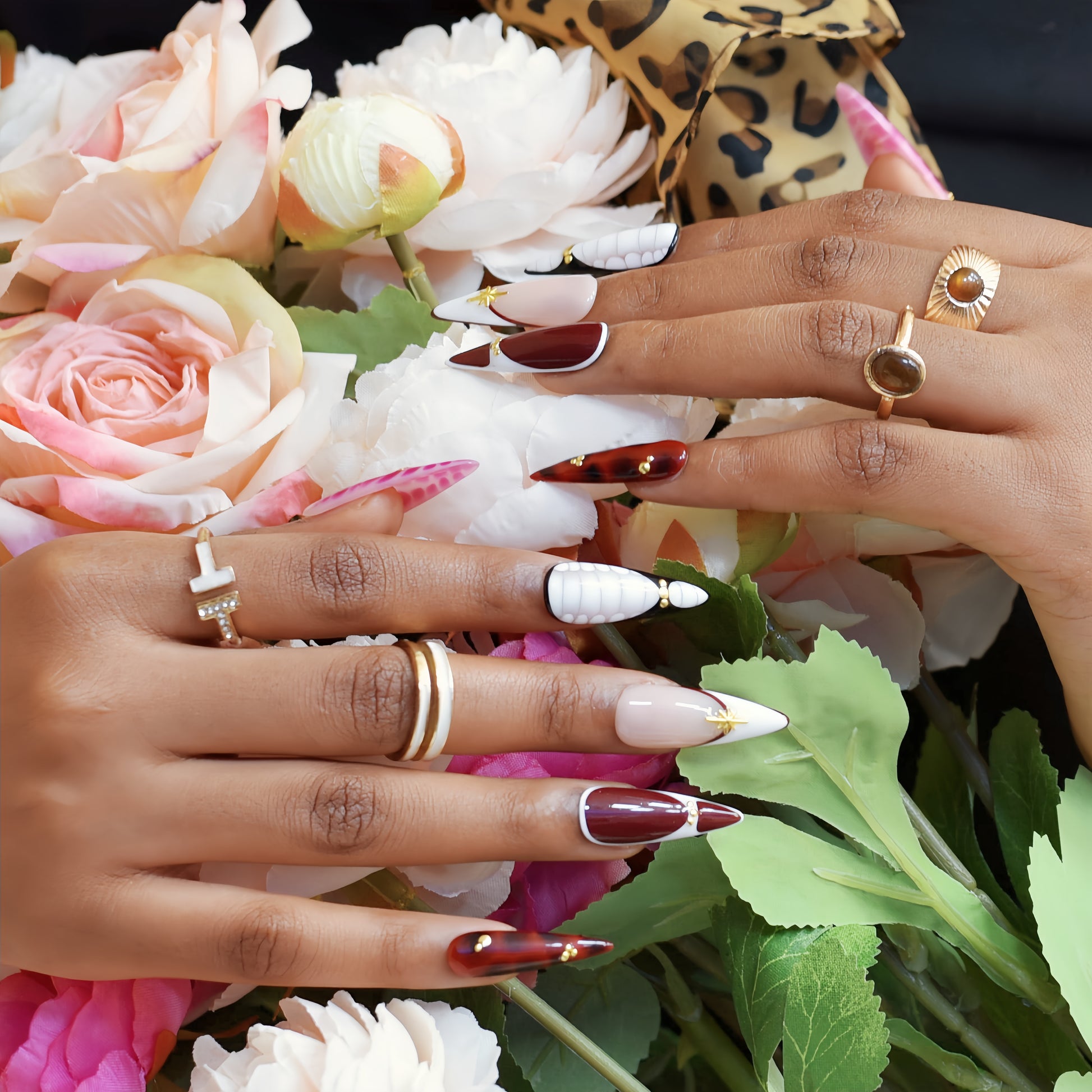 Hands wearing Crimson Elegance stiletto press-on nails in deep red and white with gold accents, styled with rings for a luxurious look.