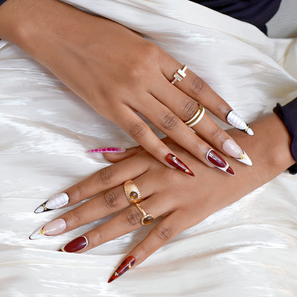 Hands wearing Crimson Elegance stiletto press-on nails in deep red and white with gold accents, styled with rings for a luxurious look.